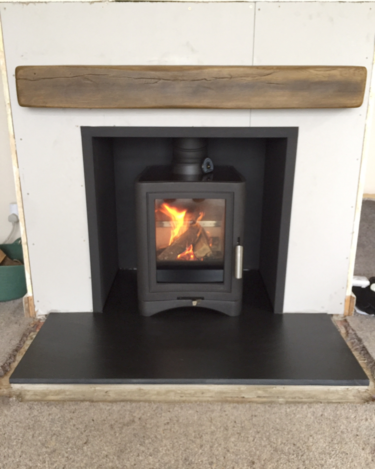 Multi fuel stove installed on a slate hearth under an oak beam